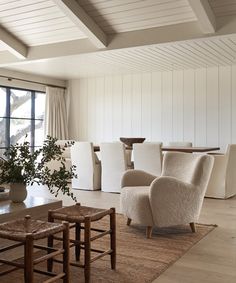 a living room filled with furniture next to a large window and a wooden table topped with a potted plant