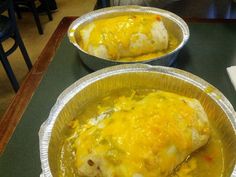 two foil containers filled with food sitting on top of a table