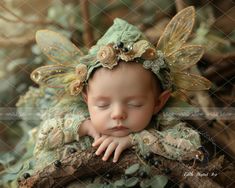 a baby sleeping on top of a tree branch wearing a green fairy dress and headband