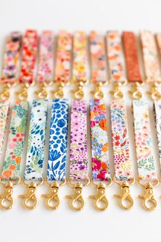 a bunch of different colored lanyards with gold hooks on each side and flowers all over them