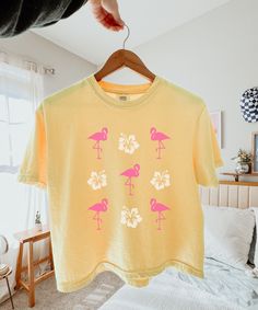 Flamingo Shirt Women Semi Cropped Tee Hibiscus Shirt Coconut Girl Beachy Shirt Flamingo Gifts Preppy Stuff Ocean Animal Shirt Teen Girl Gift An adorable flamingo and hibiscus flower semi cropped Tshirt! Printed on a Comfort Colors slightly cropped boxy fit style shirt, this new favorite is sure to be a conversation starter with other beach and animal lovers. This would also make a fun vacation shirt! Comfort Colors® is a proud member of the US Cotton Trust protocol which means this shirt is made Pink Palm Tree Print Short Sleeve Top, Printed Yellow T-shirt For Vacation, Yellow Printed T-shirt For Vacation, Pink Tropical T-shirt For Summer, Summer Pink Flamingo Print Top, Pink Cotton Top With Palm Tree Print, Spring Short Sleeve Tops With Palm Tree Print, Cotton Tropical Print T-shirt, Cotton T-shirt With Tropical Print