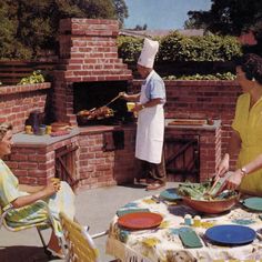 two women in aprons are cooking food on an outdoor grill while another woman watches