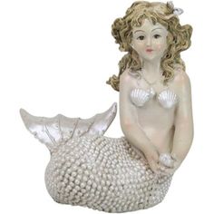 a figurine of a mermaid sitting on top of a white fish with her hair blowing in the wind