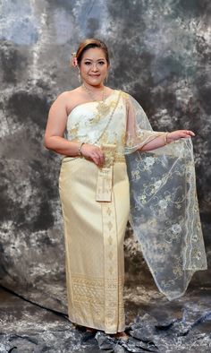 a woman in a white and gold dress with a veil on her head is posing for the camera