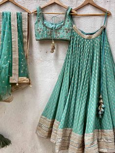 A three-piece jade green zari lehenga set from the Priti Sahni collection. This beautiful georgette small butti green lehenga with a heavy border of sequin, pearl and zari work detail with green accent is paired with a raw silk green blouse with sequin and zardosi embroidery detail all over. The lehenga has side hanging ball tassels to the waistline. And the blouse has a sequins tassel tie-up at the back. This outfit is completed with a sequin tulle dupatta with jade green accent in net material Green Georgette Lehenga With Cutdana, Green Georgette Lehenga With Cutdana Details, Green Georgette Choli With Cutdana, Pista Green Lehenga With Gota Work In Georgette, Green Floor-length Saree With Gota Work, Floor-length Green Saree With Gota Work, Green Anarkali Set With Gota Work For Reception, Green Georgette Lehenga With Traditional Drape, Green Georgette Choli For Festivals