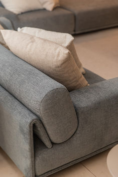 a grey couch with pillows on it in a living room or dining room area,