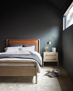 a bedroom with black walls and wooden furniture