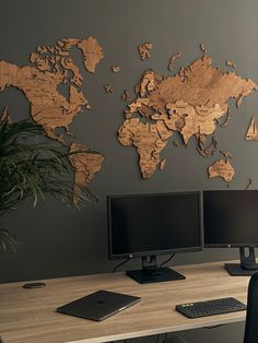 a desk with two computer monitors and a keyboard in front of a world map on the wall