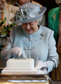 the queen is smiling as she cuts her cake