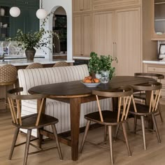 a dining room table with chairs around it in front of an island and kitchen cabinets