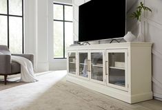 a large flat screen tv sitting on top of a white entertainment center in a living room