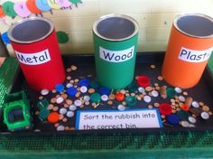 three red and green trash cans sitting on top of a black tray filled with buttons