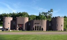 a large castle like building sitting on the side of a road next to a lush green field