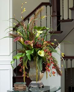 a vase filled with flowers sitting on top of a glass table next to a stair case