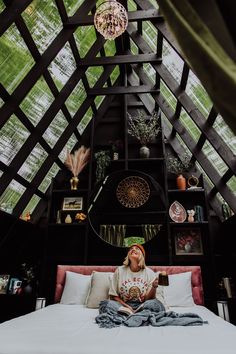 a woman sitting on top of a bed in a room with wooden walls and ceiling