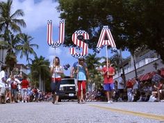 people are walking down the street with american flags in front of them and one person is holding a sign that says usa