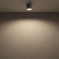 an empty room with a light on the ceiling and a wall in the back ground