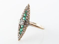 This Victorian cocktail ring features .42 carats of diamonds and .18 carats of round cut emeralds that are set in 14 karat yellow gold. The shape of the ring is a very long and slender marquise shape that runs down the finger. The primary diamond sits above the rest of the stones and weighs .22 carats. This is an elegant cocktail ring that has a very regal and historic look and would make a terrific gift!Composition: 14 Karat Yellow GoldRing Size: 5.75Primary Stone: Genuine Natural DiamondShape Fine Jewelry Marquise Cut Emerald Ring With Diamond Accents, Marquise Cut Emerald Ring With Diamond Accents, Green Diamond Ring With Rose Cut Diamonds, Green Cluster Ring With Rose Cut Diamonds, Heirloom Green Diamond Ring With Single Cut Diamonds, Green Diamond Ring With Pave Setting For Wedding, Wedding Emerald Ring With Pave Setting In 14k Gold, Marquise Emerald Diamond Ring In Yellow Gold, Yellow Gold Marquise Emerald Ring With Diamonds