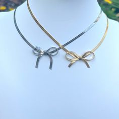 Introducing the must-have accessory of the season: our Bow Choker Necklace. Adorned with the prettiest bow, this elegant piece adds a touch of luxury to any outfit. Make a statement with this exclusive necklace, the perfect blend of fashion and art. Elevate your style with our Bow Choker Necklace today. Made to last! Non-Tarnish and Water Resistant, Hypoallergenic Heart Pendant 12.5 inches long +3.5 inches ext Lobster Closure 18K Gold Plated over 316L Stainless Steel base Elegant Gold Necklace With Decorative Bow, Adjustable Necklace With Decorative Bow For Party, Adjustable Ribbon Necklaces For Party, Gold Bow Necklace For Party, Gold Necklace With Bow For Party, Elegant Gold Necklace With Bow Detail, Elegant Gold Necklace With Bow, Adjustable Necklace With Decorative Bow, Chic Jewelry With Butterfly Knot For Parties