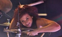 a woman is playing the drums on stage