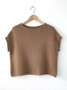 a brown crop top hanging on a white wall