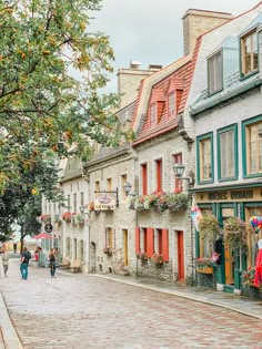 people are walking down an old cobblestone street lined with buildings and shops on either side