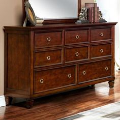 a wooden dresser sitting on top of a hard wood floor next to a mirror and clock