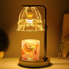 a glass jar with a candle on it sitting next to a lamp that is turned on