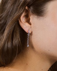 These dainty hoops are perfect for anyone who loves adding extra flair to their look! Shine and sparkle with these earrings that are studded with CZ stones and feature a dangling CZ stone charm. Materials: Rhodium plated brass, cubic zirconia Features: 1.5" drop, 0.5" hoop, 0.1" width, 3mm & 1mm CZ stones, Lead & Nickel free, friction latch Silver Dangle Hoop Earrings With Prong Setting, Sterling Silver Dangle Hoop Earrings With Sparkling Stones, Dangle Cubic Zirconia Diamond Earrings, Cubic Zirconia Dangle Diamond Earrings, Cubic Zirconia Diamond Dangle Earrings, Crystal Dangle Hoop Earrings For Pierced Ears, Dangle Diamond Earrings With Sparkling Stones, Crystal Linear Earrings With Sparkling Stones, Sparkling Stones Drop Earrings