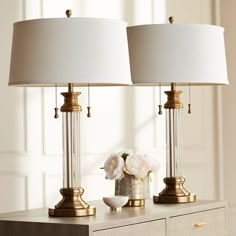 two lamps sitting on top of a table next to a vase with flowers in it