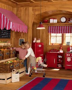 two children are playing in the kitchen with their shopping cart and food on the counter