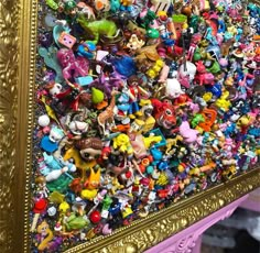 a large group of toy figurines on display in a gold frame