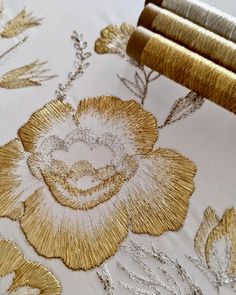 an embroidered gold flower on white fabric