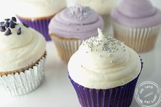 several cupcakes with white frosting and purple icing