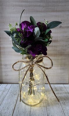 a glass jar filled with purple flowers and greenery