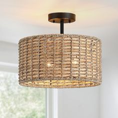 a wicker light fixture hanging from a ceiling in a room with white walls and windows