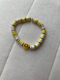 Yellow, white, and gold beaded bracelet with a classic yellow smiley face. Made with yellow, white, and gold flat clay beads. Yellow Beaded Bracelets For Everyday, Yellow Round Bead Bracelets For Everyday, Yellow Round Beads Bracelet For Everyday, Yellow Beaded Bracelets With Round Beads For Everyday, Casual Round Yellow Jewelry, Casual Yellow Round Jewelry, Casual Yellow Bracelets With Letter Beads, Trendy Yellow Stretch Bracelet For Everyday, Fun Yellow Round Beads Jewelry