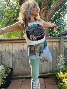 a woman standing on one leg in front of a tree with her arms spread out