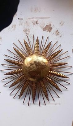 a gold sunburst on a white wall with other items in the back ground