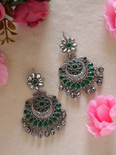 Discover elegance in our Green Ethnic Silver Earrings with Ghungroos. Meticulously handcrafted, these earrings seamlessly fuse traditional charm with contemporary style. The vibrant green and silver combination, coupled with intricate ghungroos, adds a unique flair to any outfit. Lightweight and versatile, they're perfect for both casual and formal occasions, allowing you to effortlessly embrace cultural sophistication. Elevate your style with these statement earrings that blend tradition and modernity with finesse. Available in two more stunning colour options.  In case of any queries, please feel free to contact us. Happy shopping! Temple Jewelry Style Round Oxidized Danglers, Silver Chandelier Earrings With Cutdana For Festive Occasions, Green Aesthetic Earrings, Green Jhumka Earrings, Silver Chandelier Earrings With Cutdana For Festivals, Festive Chandbali Bridal Earrings With Oxidized Finish, Silver Cutdana Chandelier Earrings For Festive Occasions, Silver Earrings With Cutdana For Gift, Silver Chandbali Chandelier Earrings With Cutdana