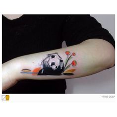 a person with a panda bear tattoo on their arm and the other hand is holding an orange flower