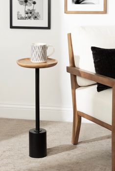 a coffee cup sitting on top of a wooden table next to a white couch and framed pictures