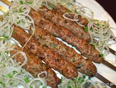 several skewered meats are on a plate with onions and parmesan cheese