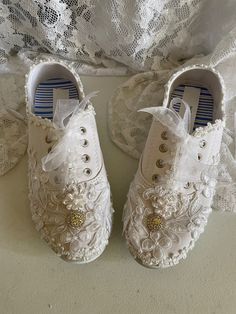 two pairs of white shoes with lace on them