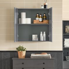 a shelf with bottles, towels and other items on it next to a dresser in a bathroom