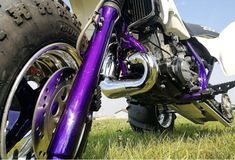 a purple motorcycle parked on top of a lush green field