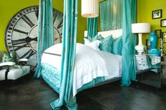 a green bedroom with four poster bed and blue drapes on the ceiling, along with white pillows