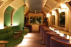 the interior of a train car with green seats and round tables on either side of it