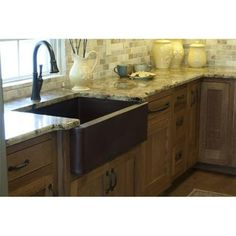 a kitchen with marble counter tops and wooden cabinets, an apron sink and black faucet