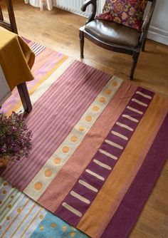 a room with a chair, table and rug on the floor